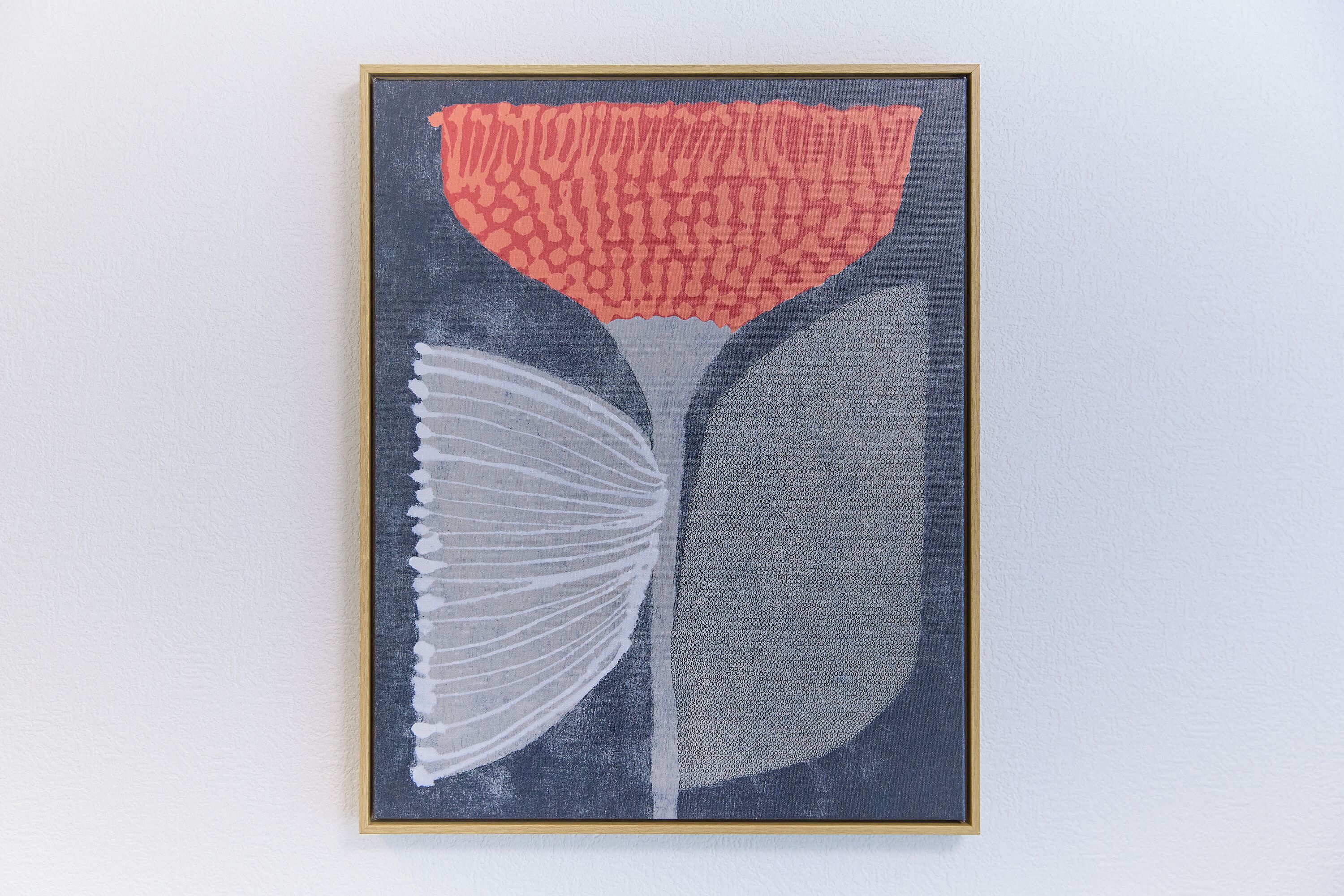 A framed abstract artwork with a dark background and a central red pattern.