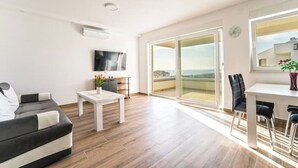 A modern living room with a sofa, a coffee table, and a dining area with chairs. - Apartment 3 (Novalja)
