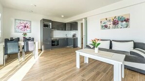 A modern living room with a dining area, a kitchen, and a sofa. - Apartment 3 (Novalja)