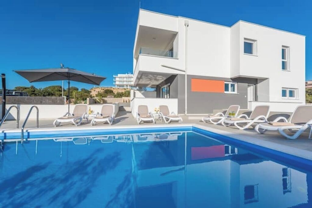 A modern poolside area with lounge chairs and a clear blue pool.
