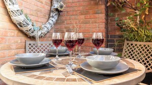 Una mesa redonda con un diseño de mosaico, rodeada de cuencos grises y copas de vino llenas de vino tinto.