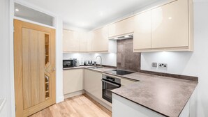 Una cocina moderna con armarios blancos, una puerta de madera y una encimera.