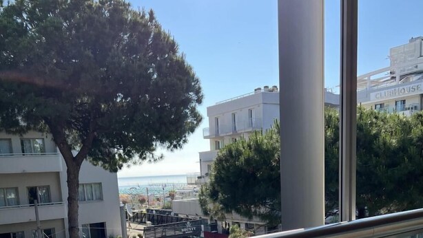 A view from a balcony overlooking a coastal area with buildings, a tree, and a clear sky. - Vespucci Home – Elegance (Rimini)