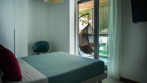 A bedroom with a bed, a chair, and a window with a view of greenery. - Vespucci Home – Elegance (Rimini)