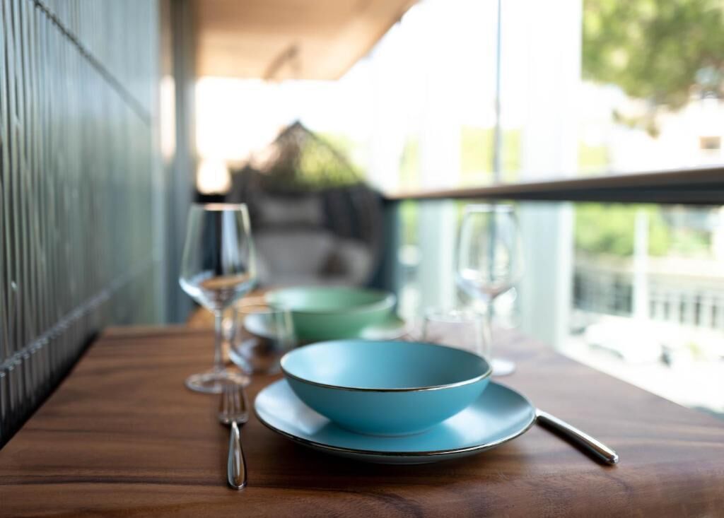 A dining table with a blue bowl and plate, a fork, and a glass on a wooden surface.