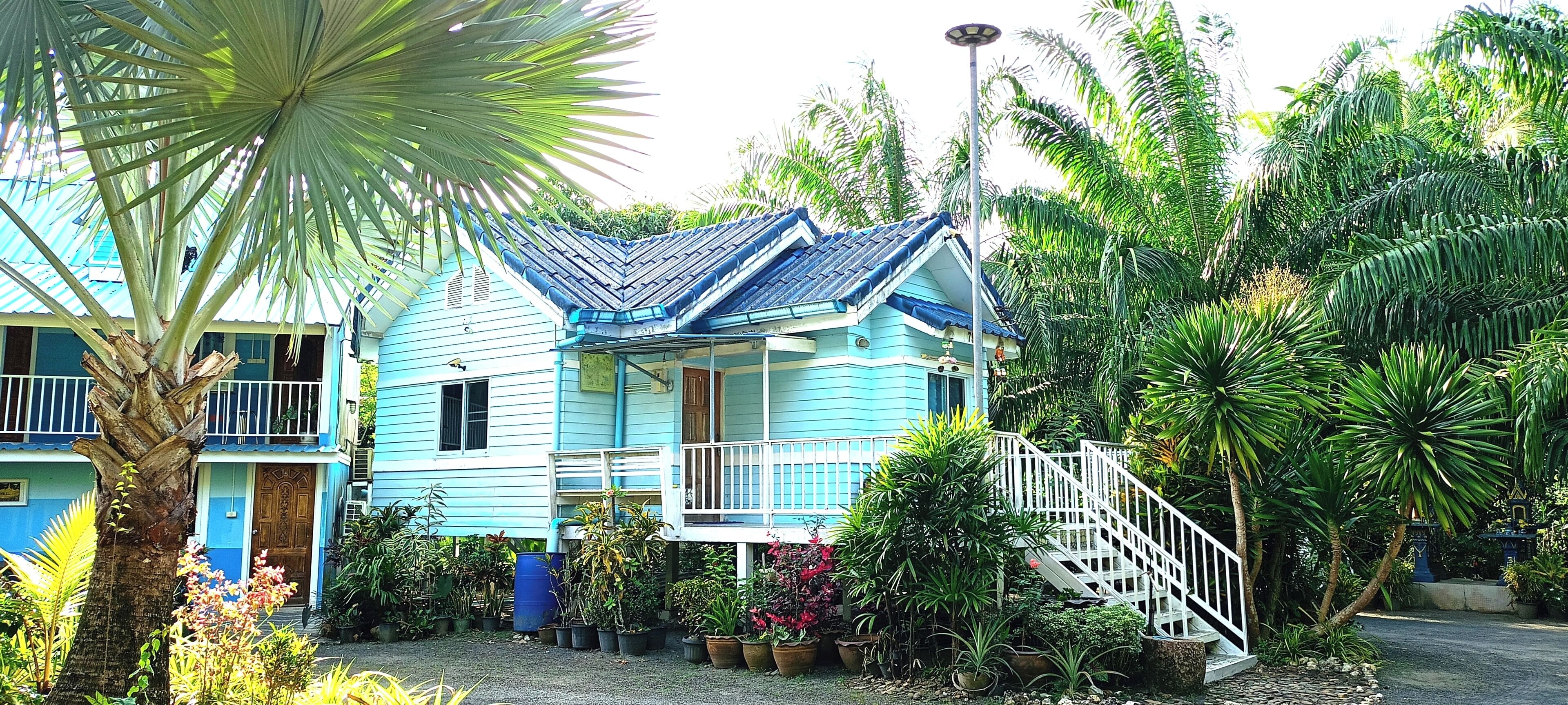 Una casa de dos pisos con fachada azul y balcón blanco.