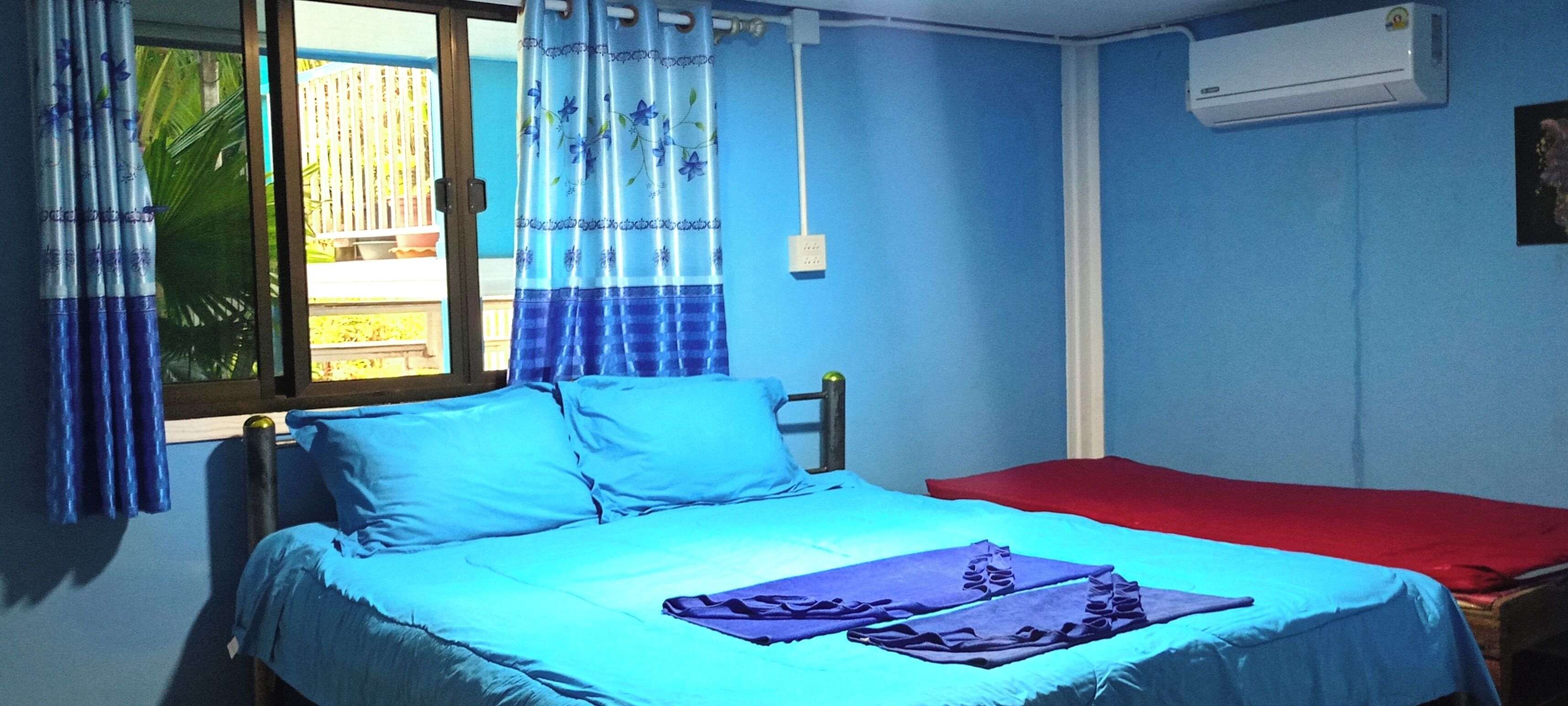 Una habitación con una cama, un tapete rojo y un aire acondicionado en la pared.