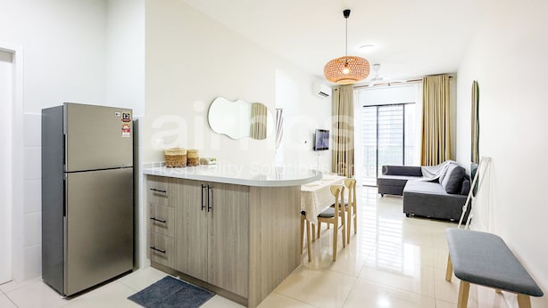 A modern kitchen with a built-in refrigerator, wooden cabinets, and a central island with stools. - Vista Sentul Residences by Airhost (Kuala Lumpur)
