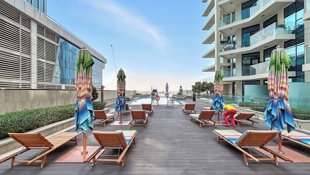 A rooftop pool area with lounge chairs and umbrellas, surrounded by modern buildings. - Luxury Suite Canal Views Infinity Pool (Dubai)