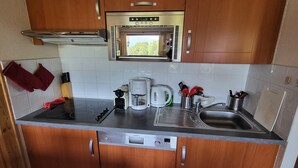 A compact kitchen with a built-in microwave, a coffee maker, a toaster, and a sink. - Peaceful Mountain Apartment in Morillon (Morillon)