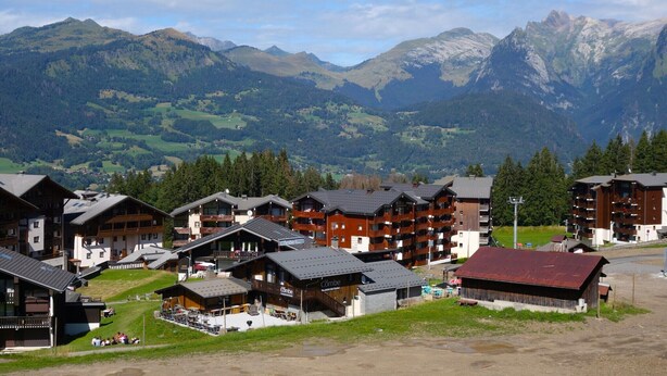 A mountain resort with chalet-style buildings, outdoor seating areas, and a view of the surrounding mountains. - Peaceful Mountain Apartment in Morillon (Morillon)