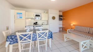 Un espacio habitable compacto con kitchenette, comedor y sofá.