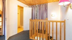 Ett rum med ett träpanelat tak, ett träräcke, en vit dörr och en randig gardin.
