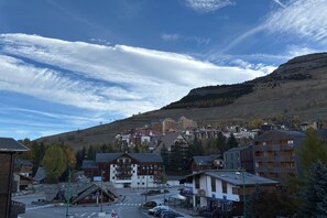 Un pueblo con una mezcla de edificios modernos y tradicionales, un cielo despejado y un paisaje montañoso al fondo.
