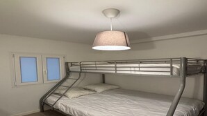A bunk bed with a metal frame, a white mattress, and a hanging lamp. There are two windows with blue blinds. - Les Marmottes N°302 - 2P7 (Les Deux Alpes)