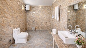 A bathroom with a marble wall, a toilet, a sink, and a shower. - Rambagh Retreat-Stay with  Swimming Pool (Udaipur)