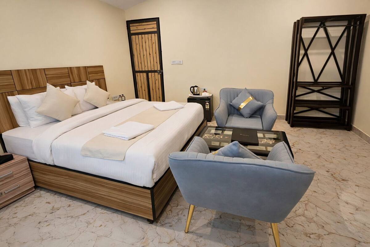 A bedroom with a bed, a chair, a coffee table, and a wardrobe.