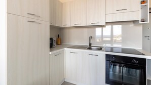 A modern kitchen with white cabinetry, a built-in microwave, a stainless steel sink, and a black dishwasher. - Air conditioning, swimming pool and parking space (Castelsardo)
