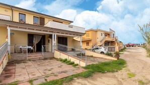 A residential building with a covered patio, a staircase, and a dirt path. - With air conditioning and private terrace (Castelsardo)