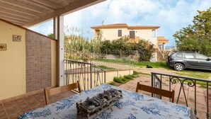 A covered patio with a table set for dining, a view of a house, and a parked car. - With air conditioning and private terrace (Castelsardo)