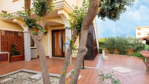 A courtyard with tiled flooring, a wooden door, and a stone pillar. - Aria condizionata e ampio spazio esterno (Castelsardo)