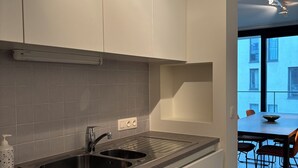 A modern kitchen with white cabinets, a stainless steel sink, and a grey countertop. - La Petite Foret Modern Flat Near Historic Bruges (Bruges)