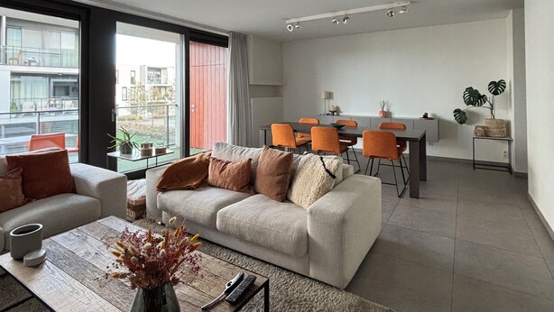 A modern living room with a sofa, coffee table, and dining area. - La Petite Foret Modern Flat Near Historic Bruges (Bruges)