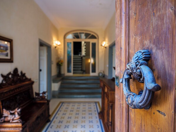 A wooden door with a lion head knocker, a patterned rug, and a staircase leading to a second floor.