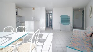 Un espacio habitable moderno y bien iluminado con una mesa de comedor, sillas, un sofá y una cocina al fondo.