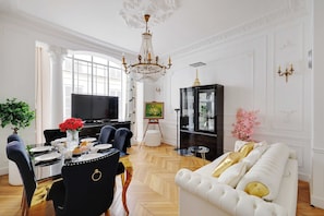 A dining area with a chandelier, a piano, and a television.