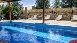 Ein Schwimmbecken mit Steinwänden und Liegestühlen.