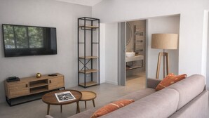 Un salon moderne avec un canapé gris, une table basse en bois, un téléviseur et une bibliothèque.