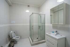 Ein Badezimmer mit Duschkabine, Toilette und Waschbecken mit Spiegel darüber.