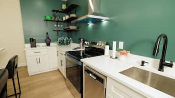 Una cocina moderna con armarios blancos, un lavamanos de acero inoxidable, un grifo negro y un horno empotrado.
