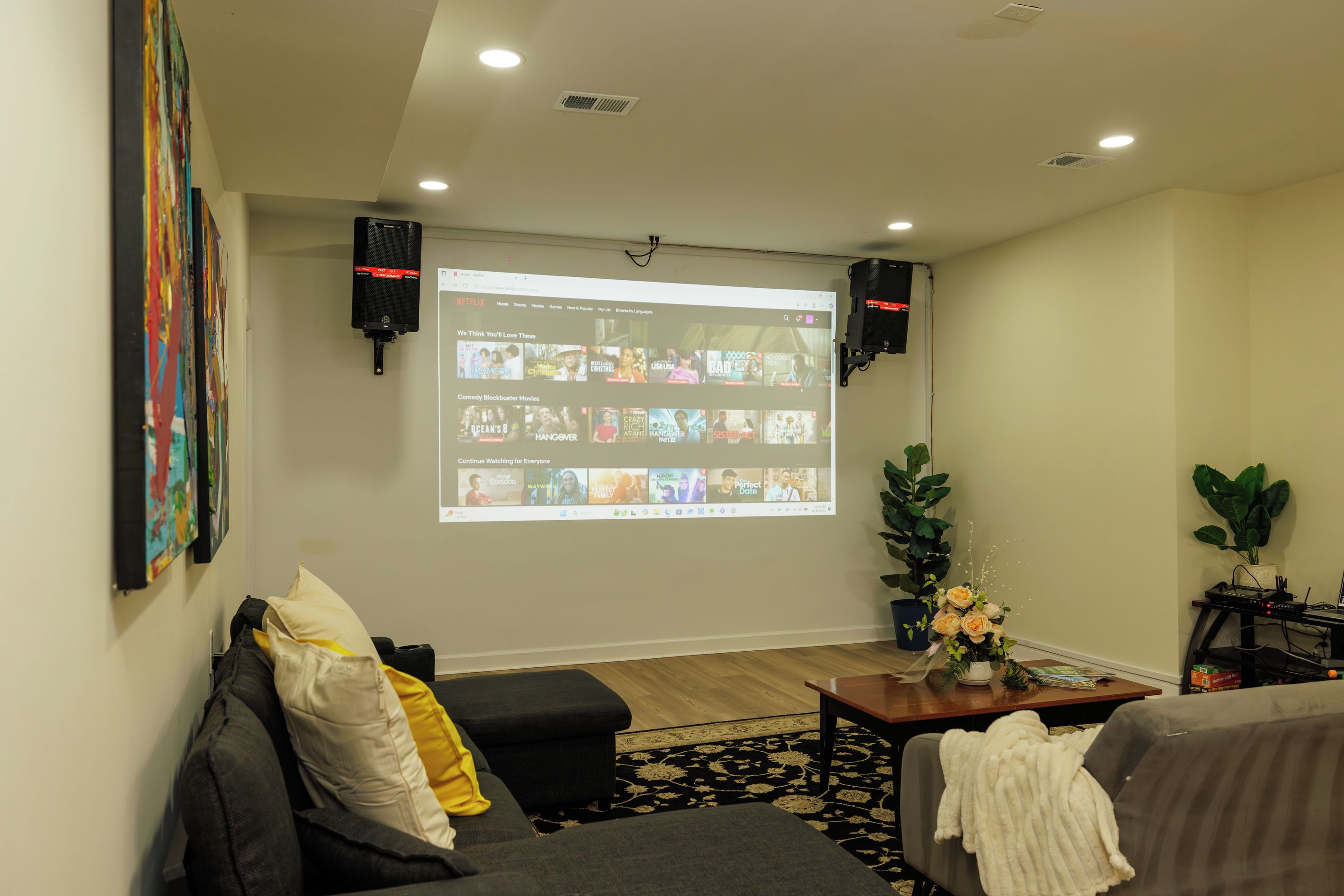 Un salon avec un grand écran affichant l’interface de Netflix, un canapé, une table basse et une plante.