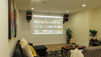 Un salon avec un grand écran affichant l’interface de Netflix, un canapé, une table basse et une plante.