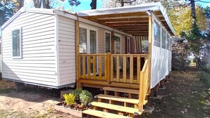Une petite maison mobile d’un seul étage, dotée d’une terrasse en bois et d’un porche couvert.