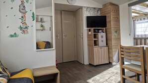 Un salon chaleureux avec un canapé, un meuble TV en bois et une bibliothèque.