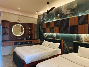 A bedroom with two beds, a round mirror, a ceiling fan, and a marble wall. - Estuary Dreamz BOATEL (Puducherry)