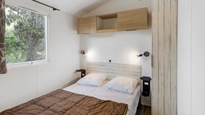 Une chambre à coucher avec un lit, une fenêtre, une étagère en bois et des lampes fixées au mur.