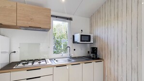 Une cuisine compacte équipée d’une cuisinière à gaz, d’un four à micro-ondes et d’une machine à café.