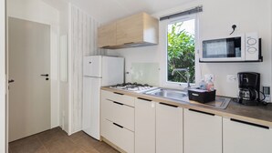 Una cocina moderna con microondas integrado, cafetera y ventana con vistas a zonas verdes.