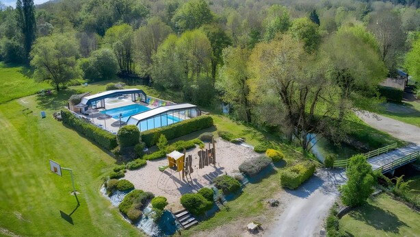 Vista aérea de una propiedad con piscina, cancha de tenis y jardín bien cuidado.