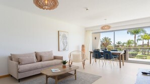 Ein modernes Wohnzimmer mit einer Couch, einem Couchtisch und einem Essbereich mit Stühlen und einem Tisch.