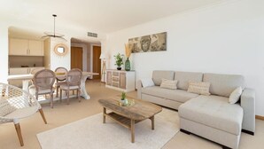 Ein modernes Wohnzimmer mit Sofa, Couchtisch und Essbereich.