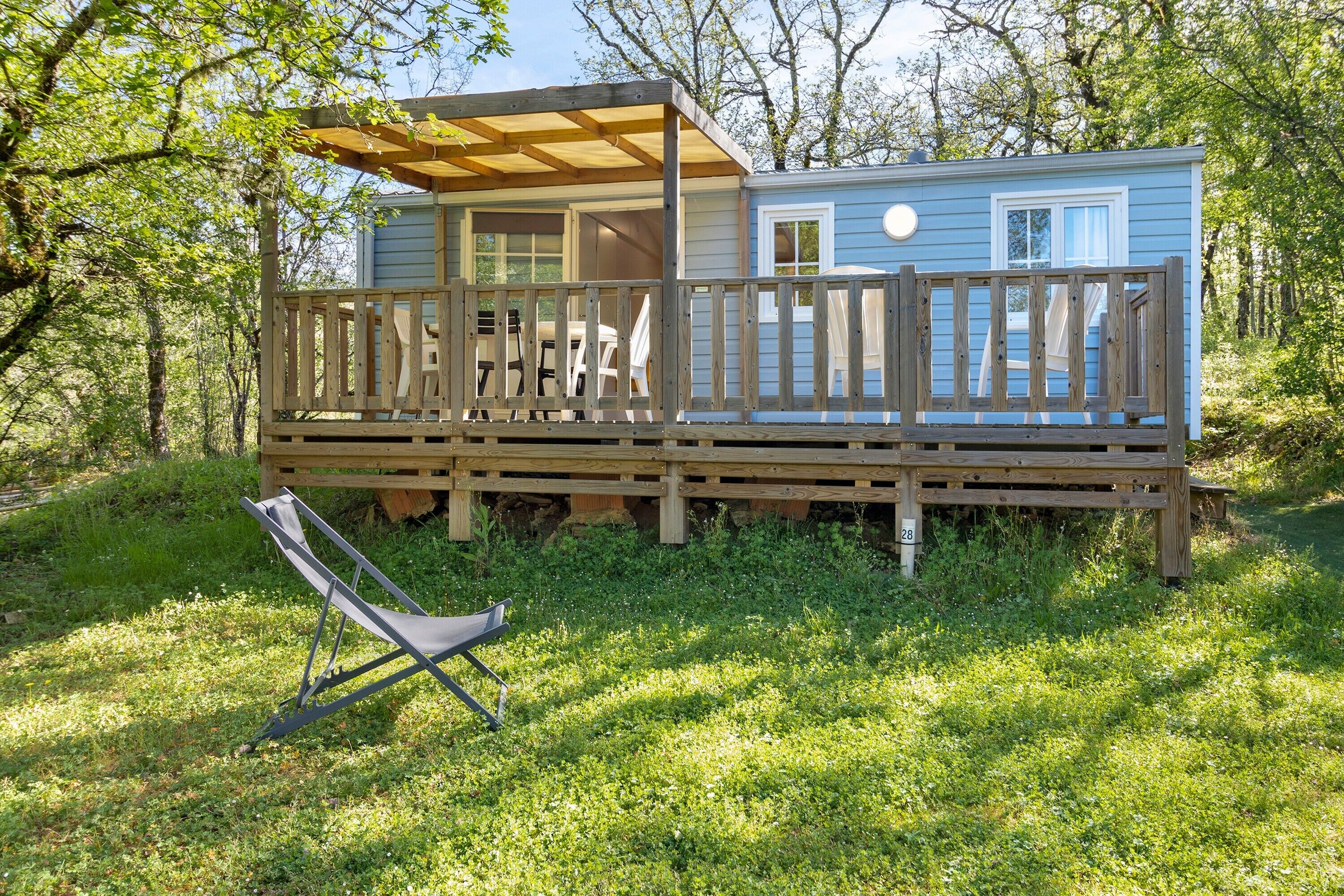 A blue cabin with a wooden deck and a covered porch.
