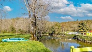 Ein Fluss mit Booten, einer Bank und Bäumen.