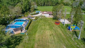 Una propiedad residencial con piscina, una casita y un trampolín.
