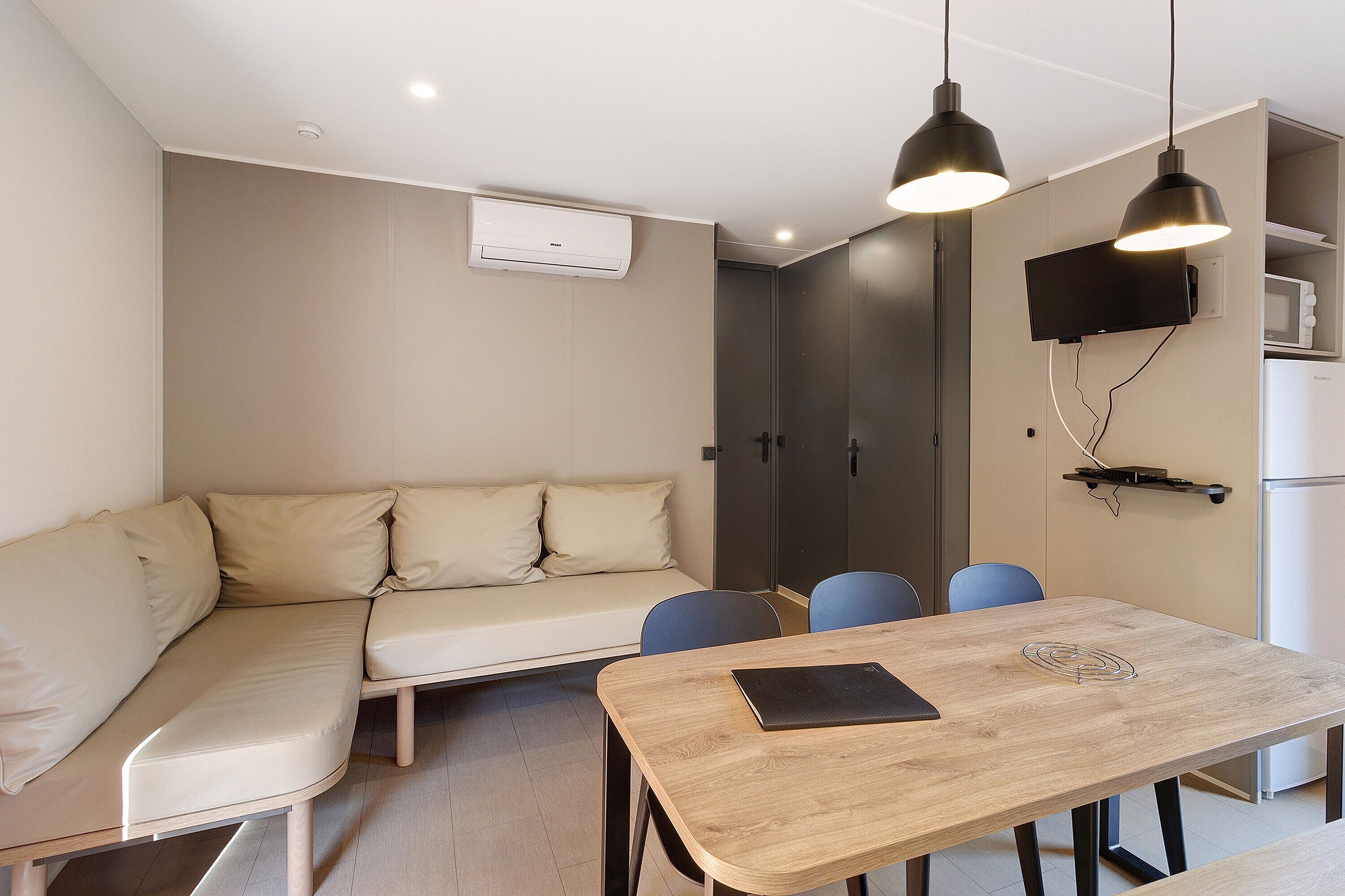 A modern room with a sofa, a wooden table, and a TV mounted on the wall.