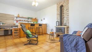 A cozy living room with a fireplace, a dining area with wooden furniture, and a kitchen with a stone accent wall. - Charming Farmhouse Retreat in Santa Ursula, Tenerife (santa ursula)